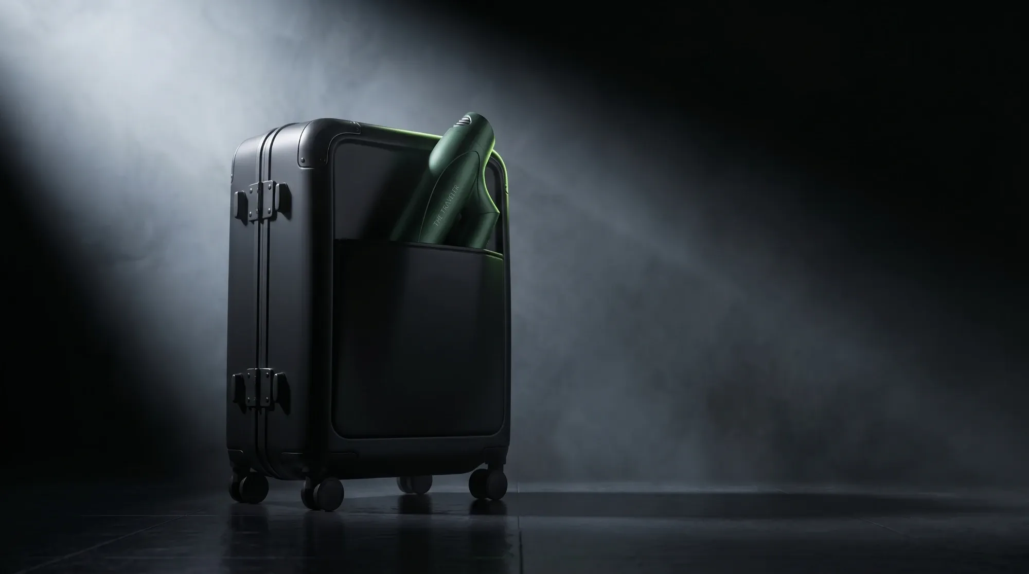 The Traveler folded into the front pocket of a black carry-on suitcase under a spotlight