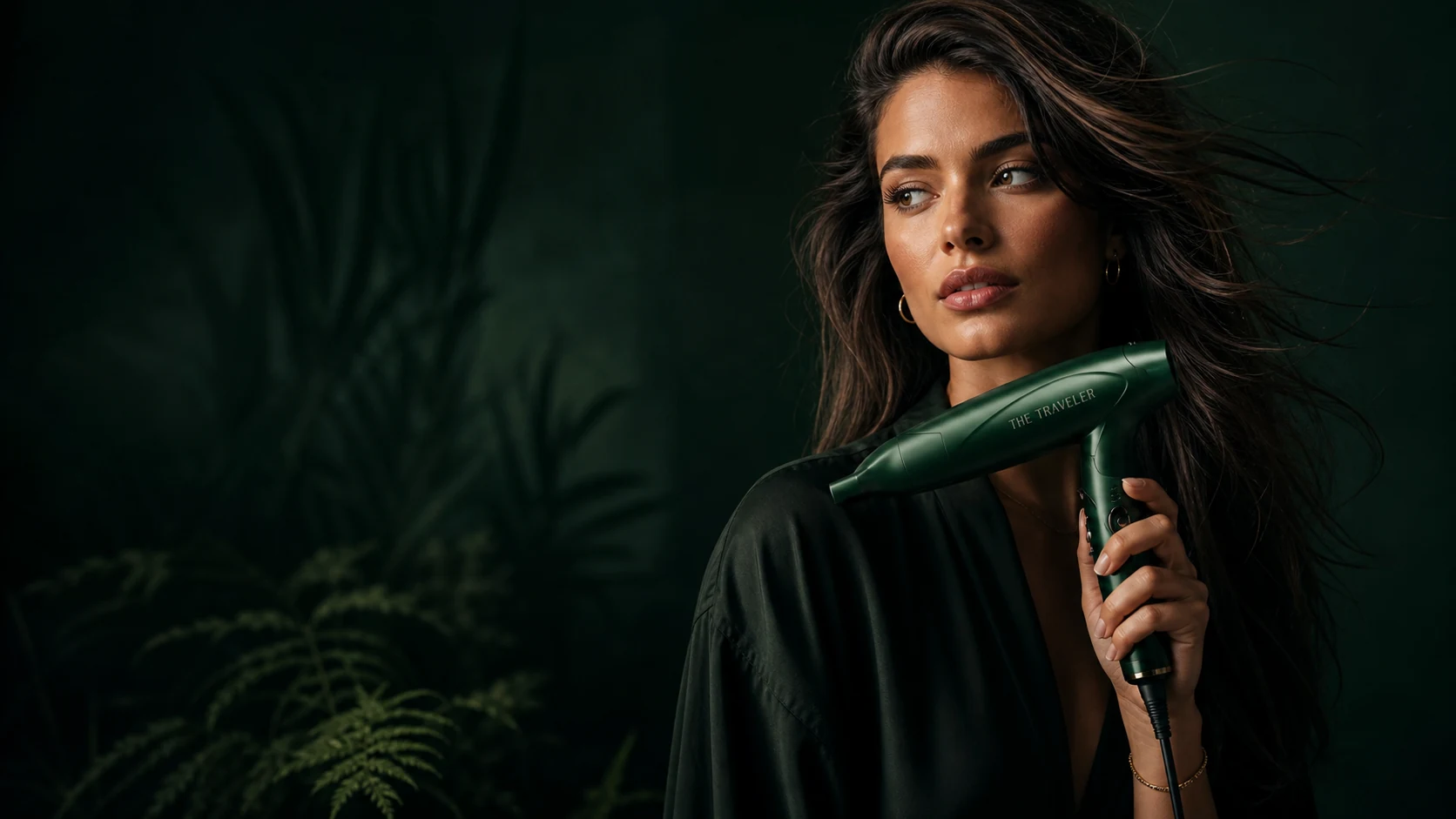 Model holding The Traveler folding hair dryer in a deep editorial setting