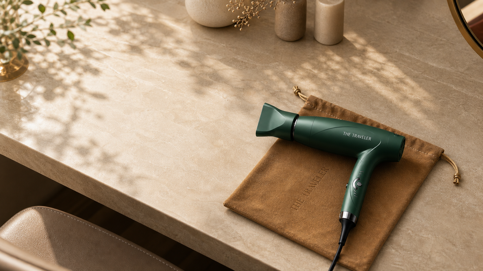 The Traveler dryer with attached nozzle resting on its tan travel bag beside the box