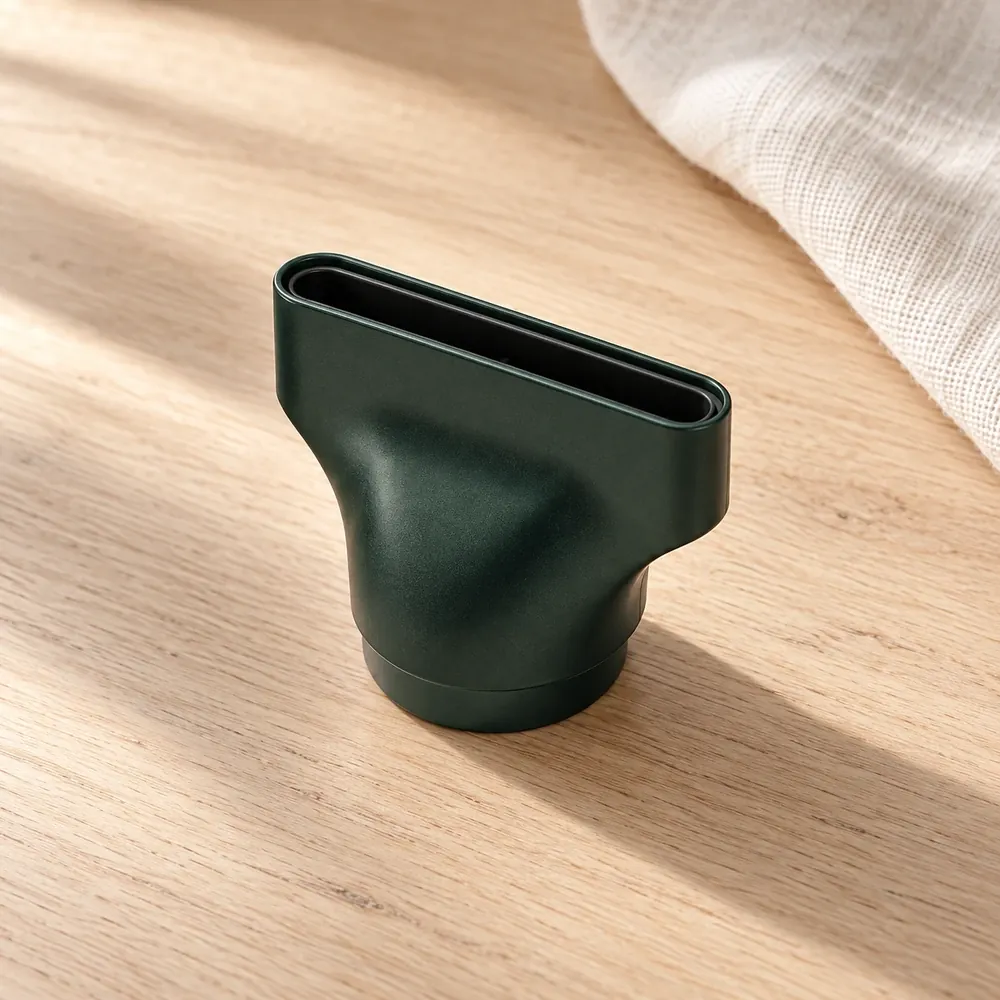 The Traveler's forest-green magnetic concentrator nozzle on a pale oak table